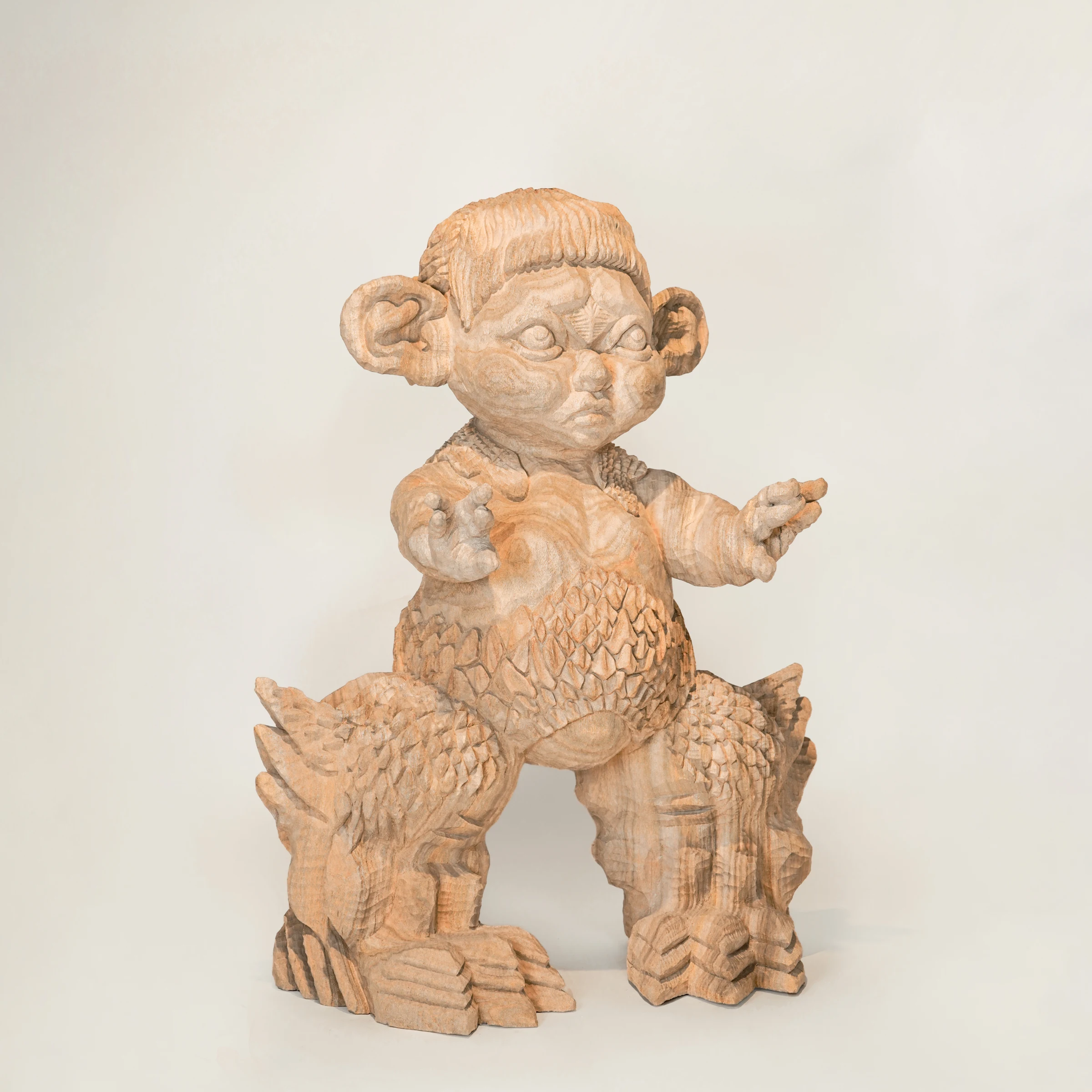 MINIRA, front view of a carved wooden figure with outstretched arms and scales