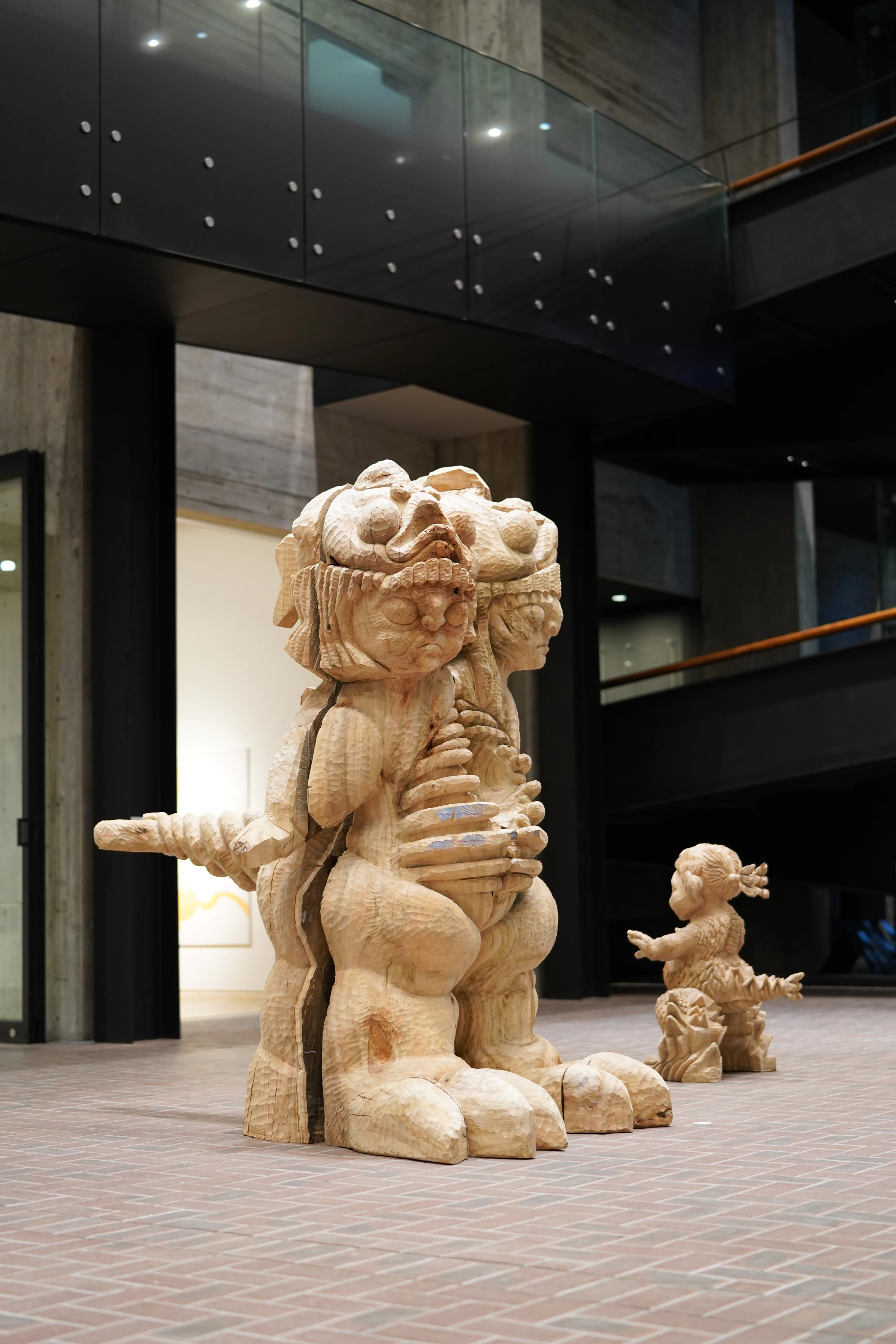 Somira, a large carved wooden sculpture with two guardian faces, displayed in an atrium